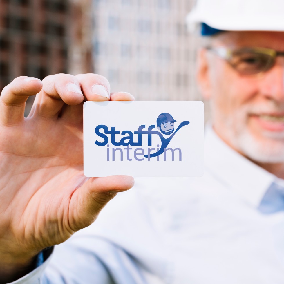 Homme avec des lunettes et un carte présente la carte de visite de Staffy Intérim