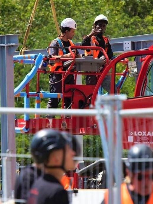 Deux ouvriers avec un casque blanc dans une nacelle rouge.